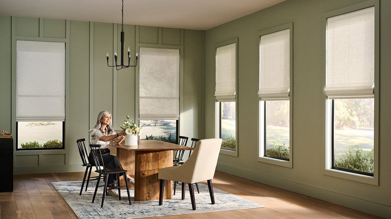 Natural woven shades filtering light in a green dining room